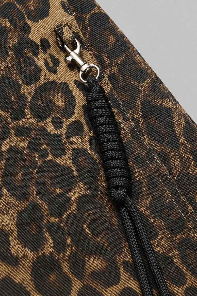Pantalon Y2K édition 'Leopard Wild', détail du motif et du mousqueton, sur fond studio gris clair.