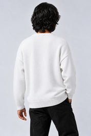 Pull blanc à emblème noir, dos uni porté sur fond gris clair — Y2K CLUB
