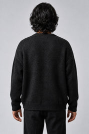 Pull Cosmic noir en maille, porté de dos sur fond gris clair
