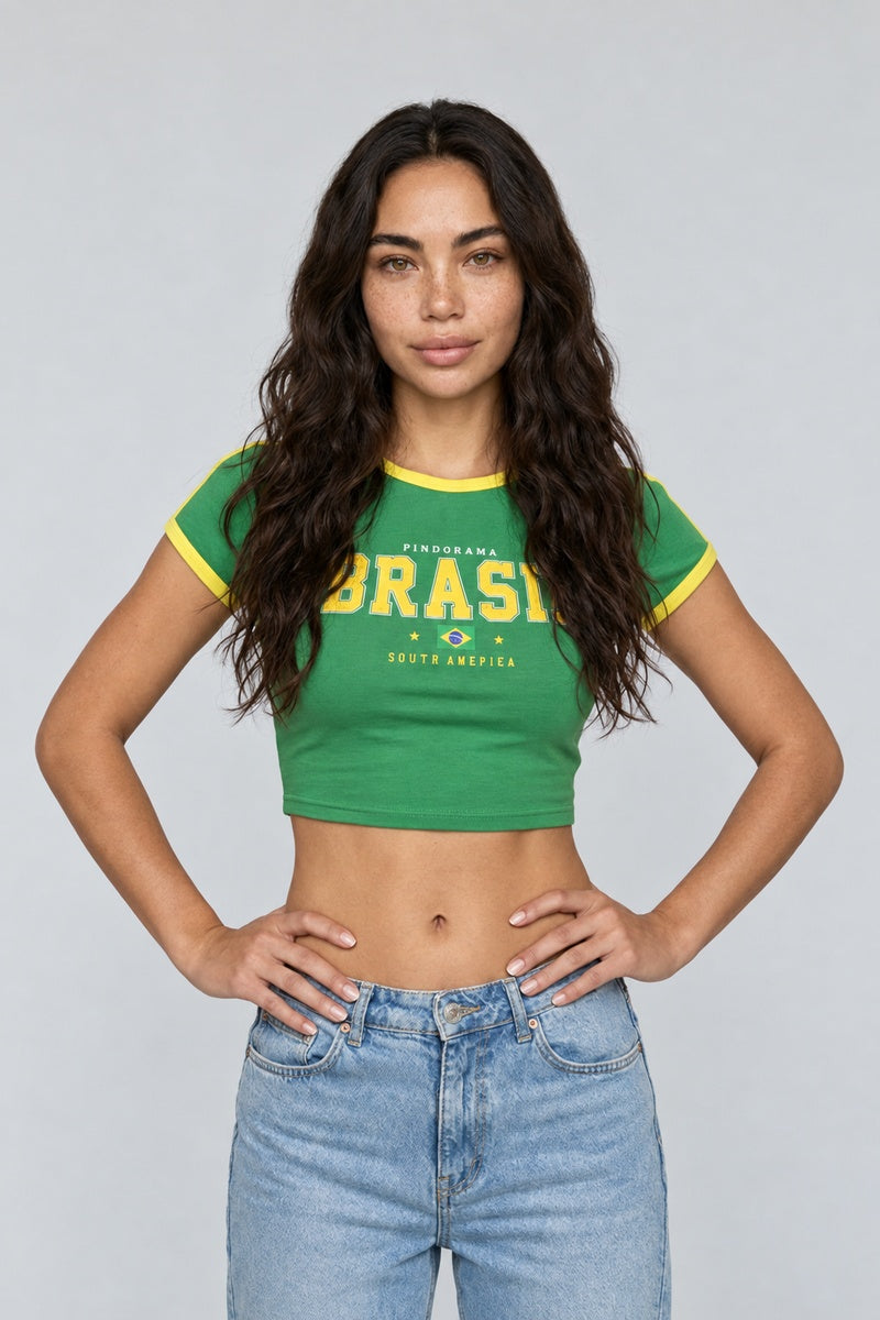 Baby tee Brésil vert à bordures jaunes et imprimé Brasil, porté de face avec un jean bleu.