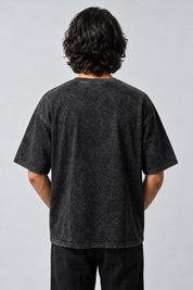 Dos uni du t-shirt oversize gris anthracite délavé, porté sur fond gris perle.