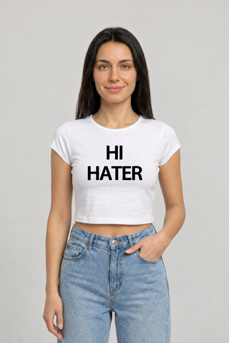 Baby tee blanc avec inscription noire HI HATER, porté de face avec un jean bleu.
