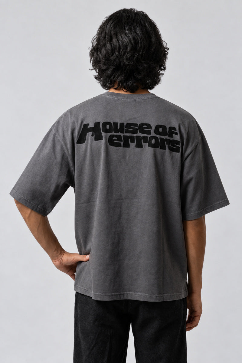 T-shirt gris oversize avec inscription noire « House of errors » en haut du dos.