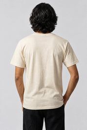 T-shirt écru à dos uni, porté de dos sur fond gris perle.