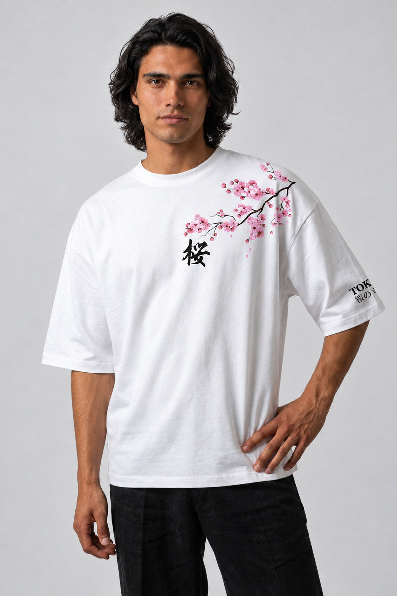 T-shirt blanc oversize avec fleurs de cerisier roses, caractère japonais et inscription sur la manche, vue de face.