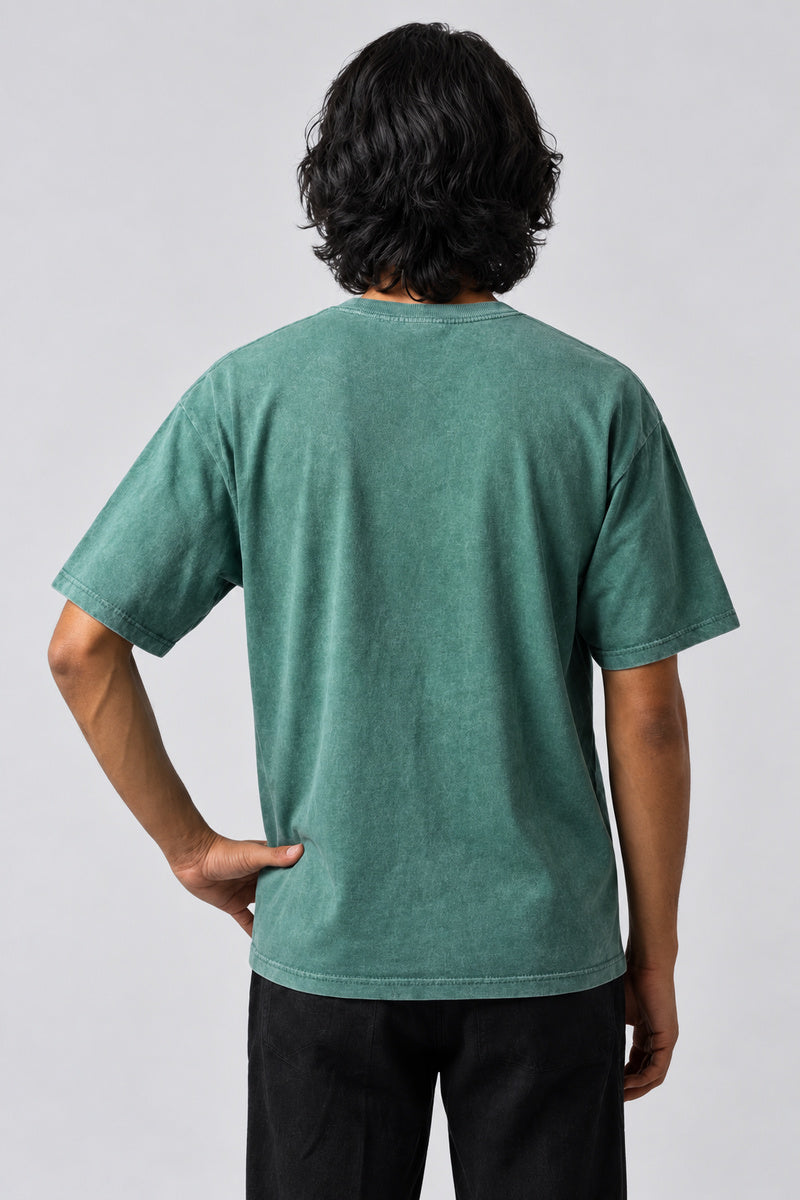 Dos uni du t-shirt Washed Vintage vert délavé, porté avec une main sur la hanche.